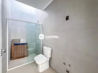 Foto de um banheiro com box de vidro e vaso sanitário branco.