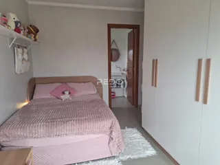Quarto com cama rosa e armário branco em um imóvel.