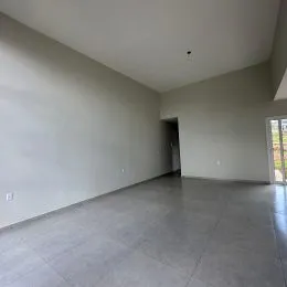 Ambiente interno amplo com paredes claras e piso cinza.