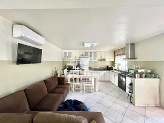 Vista interna de uma sala de estar com cozinha e sala de jantar em um apartamento.