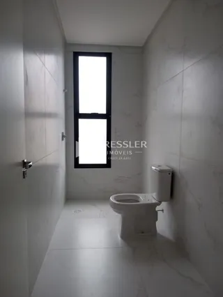 Corredor interno com piso de mármore e vaso sanitário branco.