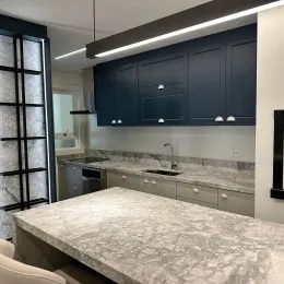 Vista de uma bancada de cozinha com armários escuros.