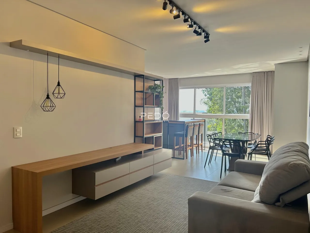 Sala de estar com ambiente integrado e piso de madeira clara.