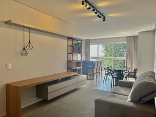 Sala de estar com ambiente integrado e piso de madeira clara.