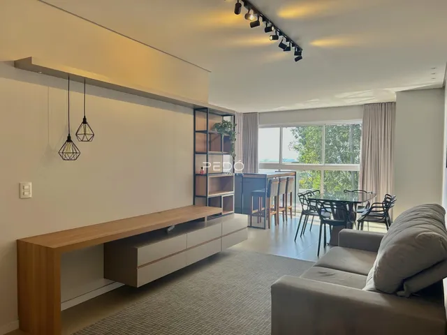 Sala de estar com ambiente integrado e piso de madeira clara.