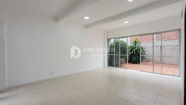 Sala ampla com piso de cerâmica e porta de vidro que dá para o exterior.