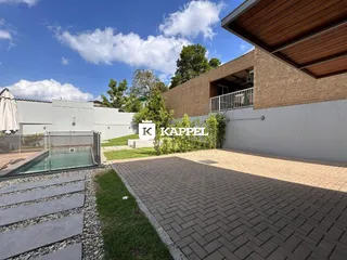Fachada de uma residência com área externa pavimentada e jardim.