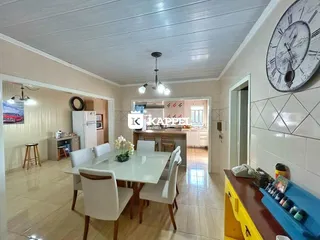 Uma sala de jantar com mesa branca e cadeiras brancas em um imóvel em Lajeado.