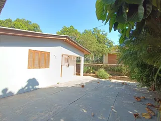 Fachada externa de uma casa branca com piso de concreto em Lajeado.