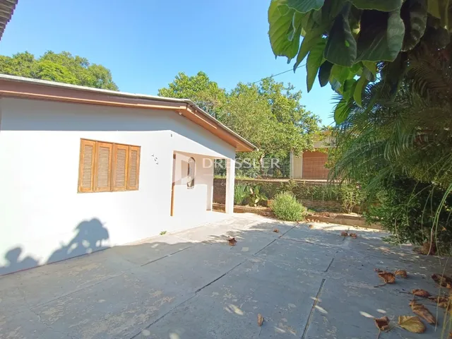 Fachada externa de uma casa branca com piso de concreto em Lajeado.