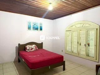 Quarto com cama de madeira e cabeceira em ambiente claro.