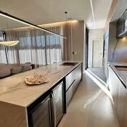 Foto de uma cozinha moderna com bancada clara e armários escuros.