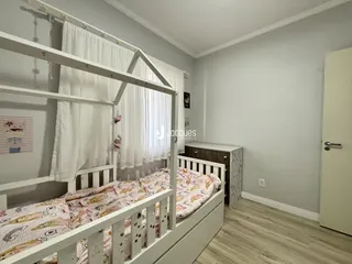Foto de um quarto com cama de madeira branca e paredes claras.
