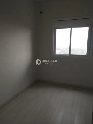 Ambiente interno de uma sala com piso de madeira clara e janela.