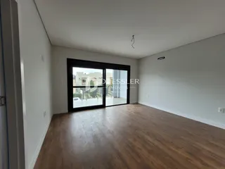 Ambiente interno de uma sala com piso de madeira e porta de vidro.