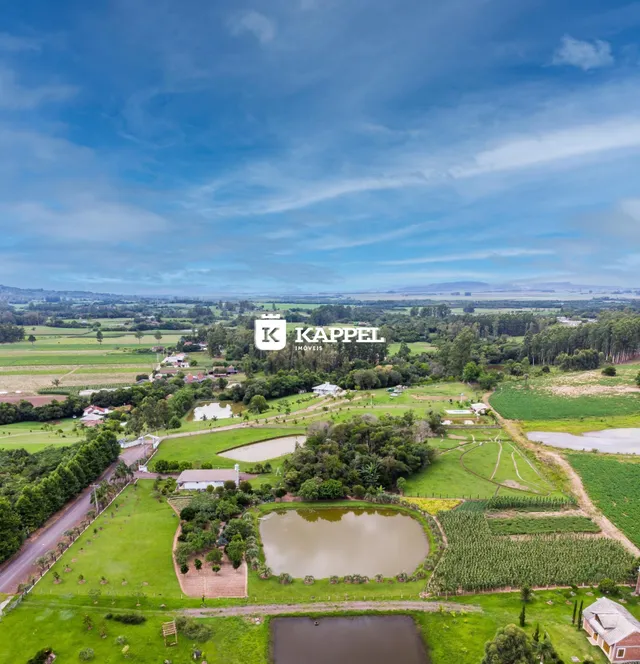 Vista aérea de uma propriedade rural com campos verdes e corpos d'água.