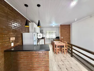 Cozinha com bancada escura e mesa de jantar de madeira em um apartamento.