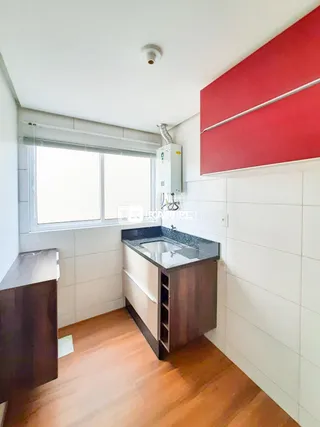 Cozinha com bancada de granito e piso de madeira clara.