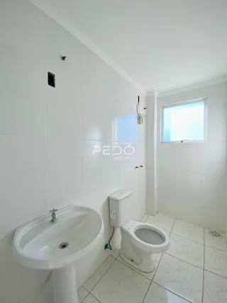 Banheiro com pia e vaso sanitário brancos em um imóvel.