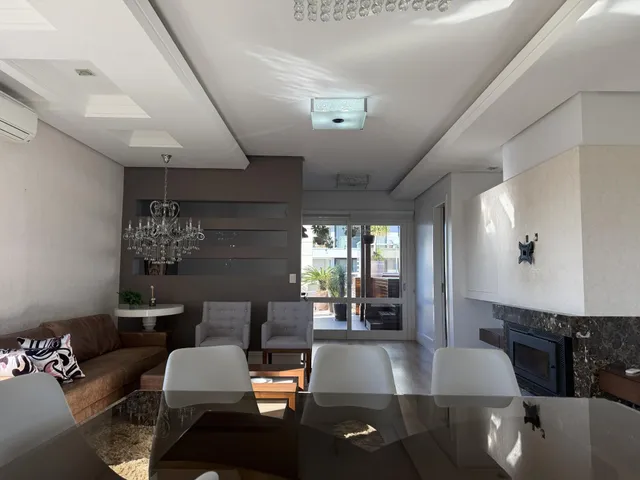 Sala de estar moderna com sofá, poltronas e lareira.