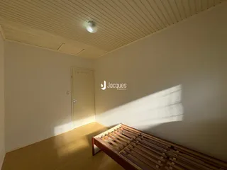 Quarto com piso de madeira e porta branca na parede.