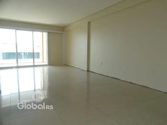 Ambiente interno de uma sala ampla com piso claro e grande janela.