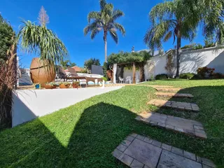 Vista externa de um jardim com gramado verde e parede branca em Lajeado.