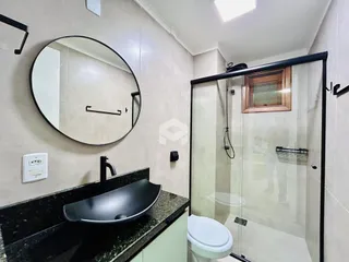 Foto de um banheiro com box de vidro e pia.