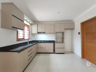 Vista da cozinha com armários e bancadas claras.