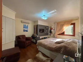 Quarto com cama e piso de madeira no interior da residência.