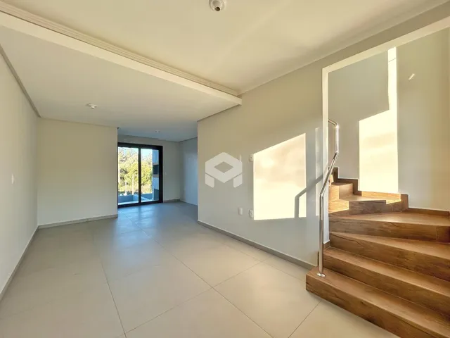 Vista de um corredor interno com piso de porcelanato e escadaria de madeira em um imóvel.