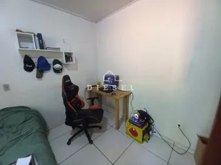 Quarto com cama, escrivaninha e prateleiras brancas em um imóvel.