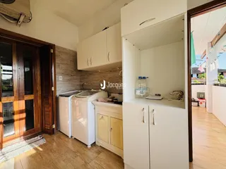 Vista interna de uma cozinha com armários brancos e piso claro.