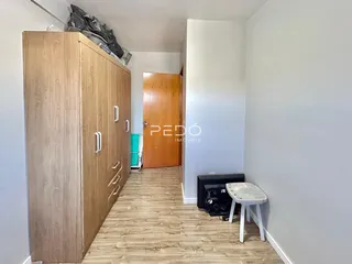 Um corredor interno com armário de madeira e piso de madeira clara.