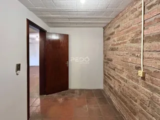 Hall de entrada com porta de madeira e parede de tijolos aparentes.
