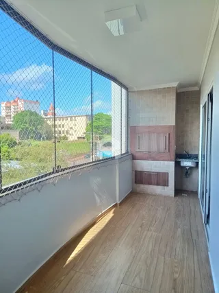 Vista interna de um cômodo com piso de madeira e grande janela.