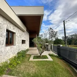 Fachada de uma residência com parede de pedra e jardim gramado.