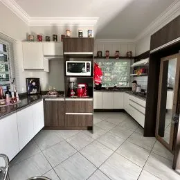 Cozinha moderna com armários brancos e bancadas escuras em um imóvel em Lajeado.