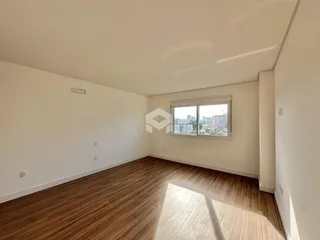 A sala de estar apresenta piso de madeira e uma grande janela com vista da cidade.