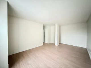 Ambiente interno com piso de madeira clara e paredes brancas.