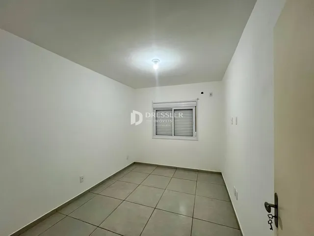 Vista de um corredor interno com piso de cerâmica e paredes brancas.