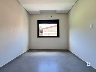 Vista de um ambiente interno com paredes brancas e piso de concreto.