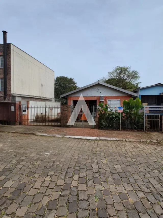 Fachada de uma residência com muro de tijolos e portão de ferro.