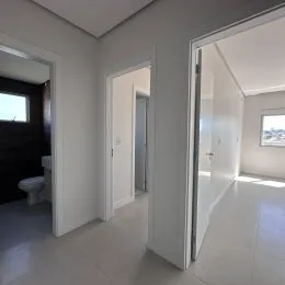Hall de passagem com paredes brancas e portas brancas.