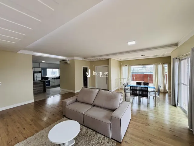 Sala de estar com piso de madeira e área de jantar.