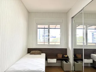 Quarto com parede ripada e janela de vista para a cidade.