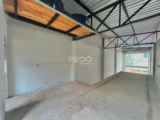 Foto de um espaço interno com estrutura de telhado metálico exposta e piso de concreto.