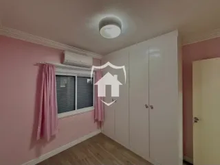 Quarto com paredes rosa e um grande guarda-roupa branco instalado.