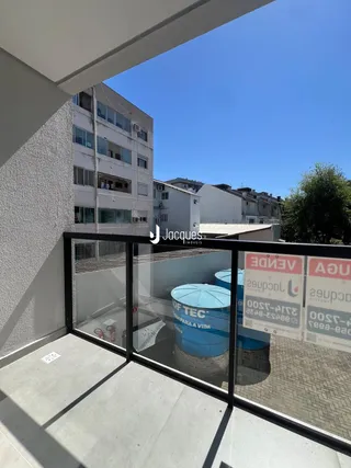 Vista da varanda mostrando tanques azuis e edifícios ao fundo.