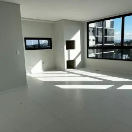 Sala de estar ampla com piso claro e grandes janelas.